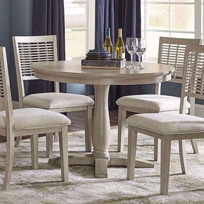 Assembled round dining table with four upholstered chairs in a bright dining room