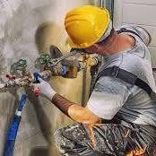 Handyman skim-coating and smoothing a repaired section of interior drywall