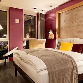 Bedroom with a deep red panelled accent wall behind an upholstered bed