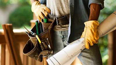 Close-up of a leather tool belt and work gloves on a job site