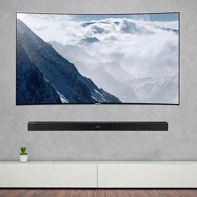 Flat-screen TV and soundbar mounted flush on a concrete feature wall above a low white media unit