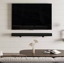 Flat-screen TV and soundbar mounted flush on a concrete feature wall above a low white media unit